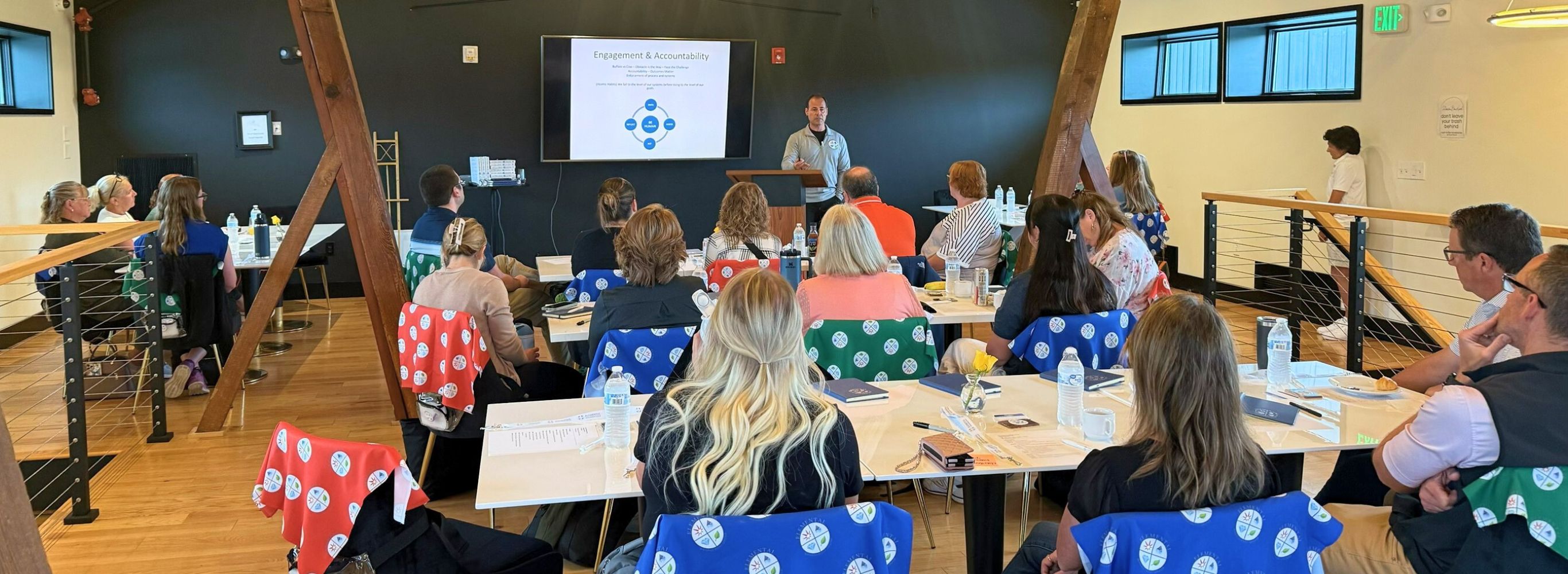 A group of people sitting at tables and listening to a speaker
