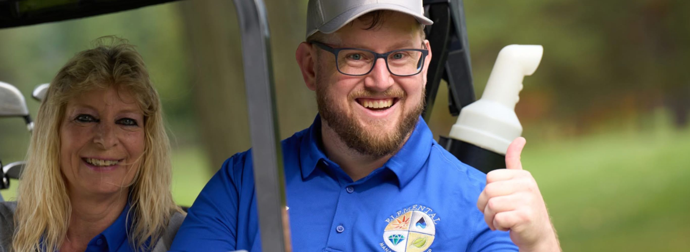 A women and a man smiling while riding a golf cart